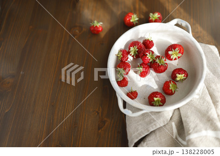 Fresh red strawberries in white ceramic vintage bowl on dark wooden table. Aesthetic food photography showcases organic summer berries for slow living breakfast and cottagecore kitchen vibes. 138228005