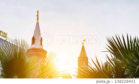 Palm trees and historic towers with golden sunlight at sunset in a vibrant city Palm trees and historic towers with golden sunlight at sunset in a vibrant city 138228431
