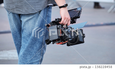 Videographer carrying professional cinema camera rig filming for media production Videographer carrying professional cinema camera rig filming for media production 138228458