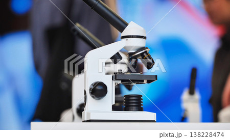 White microscope standing on a table in science lab 138228474
