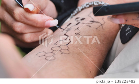 Henna artist drawing temporary mehendi pattern on skin arm at India Day 138228482