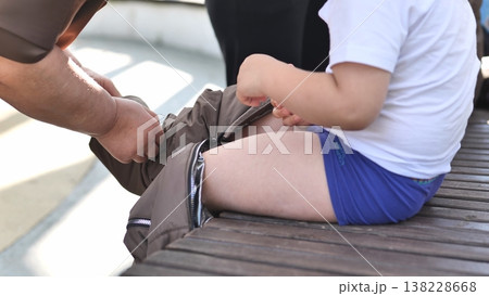 Parent helping young child getting dressed, putting on pants, care and support Parent helping young child getting dressed, putting on pants, care and support 138228668