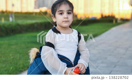Little girl standing in park looking at camera during golden hour 138228702