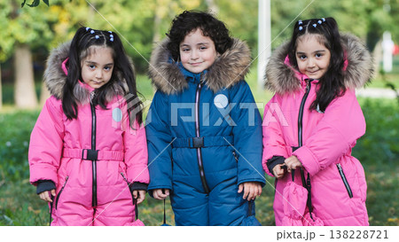 Children wearing snowsuits in park, enjoying winter clothing and friendship outdoors Children wearing snowsuits in park, enjoying winter clothing and friendship outdoors 138228721