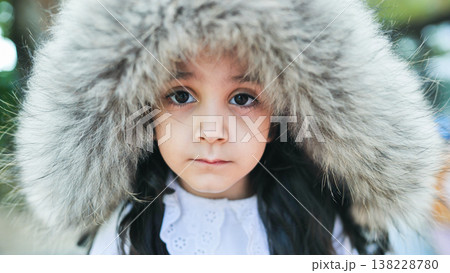 Young girl wearing fur hood showing winter warmth and childhood innocence portrait 138228780
