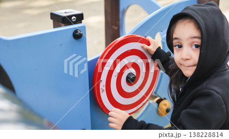 Young girl in a black hoodie playing at an outdoor park playground activity Young girl in a black hoodie playing at an outdoor park playground activity 138228814