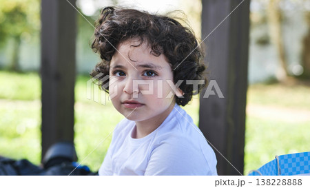 Child with curly hair exploring outdoors, looking curious and innocent 138228888