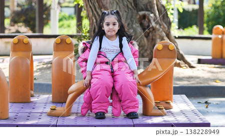 Little girl sitting on playground equipment Little girl sitting on playground equipment 138228949