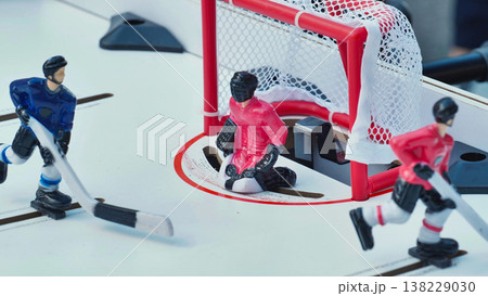 Tabletop hockey game action scene with miniature players and goalie defending the net. Tabletop hockey game action scene with miniature players and goalie defending the net. 138229030