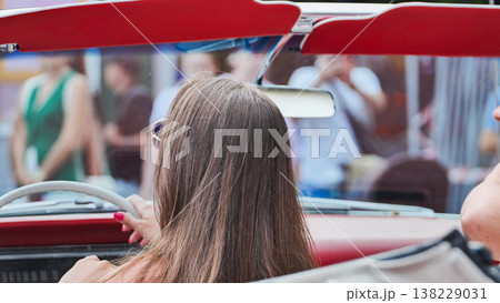 Woman enjoying a summer road trip, driving a red vintage convertible car 138229031