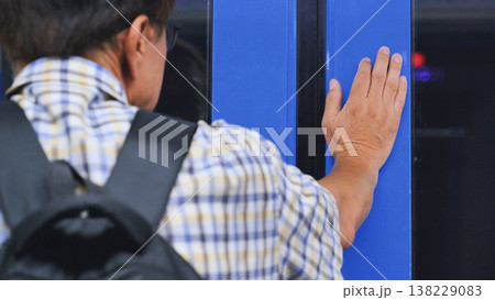 Commuting man with backpack touching train car door on public transport journey 138229083