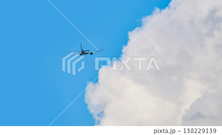 Passenger airplane flying over white cumulus clouds on clear blue sky 138229139