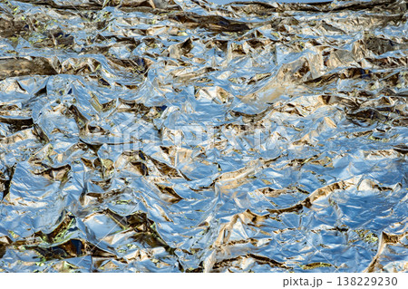 Wrinkled aluminum foil background showing abstract patterns and shiny reflections Wrinkled aluminum foil background showing abstract patterns and shiny reflections 138229230