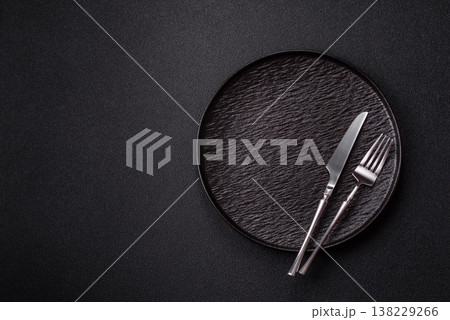 An empty round ceramic plate, knife, and fork as a dining table setting. An empty plate 138229266
