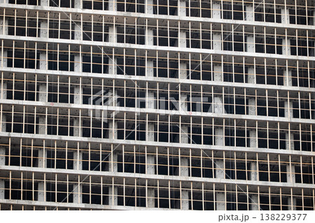Concrete building framework under construction showing grid pattern of unfinished facade Concrete building framework under construction showing grid pattern of unfinished facade 138229377