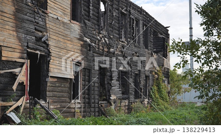 Charred remains of an old log cabin building after a fire, showing decay and ruin 138229413