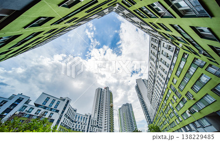 Modern residential buildings framing a view of blue sky with white clouds Modern residential buildings framing a view of blue sky with white clouds 138229485