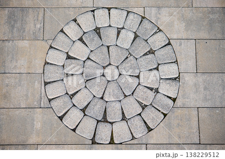 Paving stones forming a circular pattern on an outdoor walkway surface 138229512