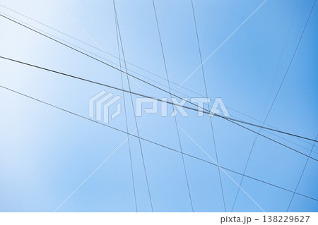 Intersecting power lines forming a grid pattern against a clear blue sky 138229627