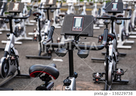 Rows of stationary bikes ready for an indoor cycling workout class in a gym 138229738