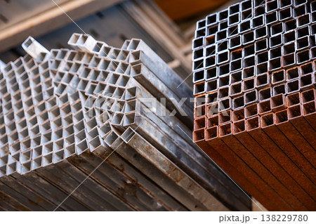 Stacked square metal profiles displaying rust and industrial texture in storage 138229780