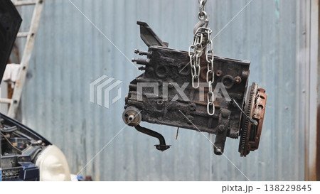 Car engine block hanging from a chain for repair 138229845