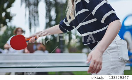 Woman holding a paddle, playing table tennis in a park for hobby and active leisure 138229847