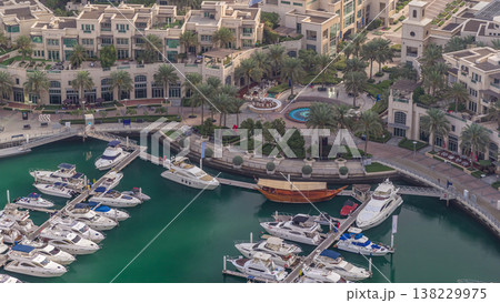 Aerial view on yachts floating in Dubai marina timelapse. White boats are in green canal water. 138229975