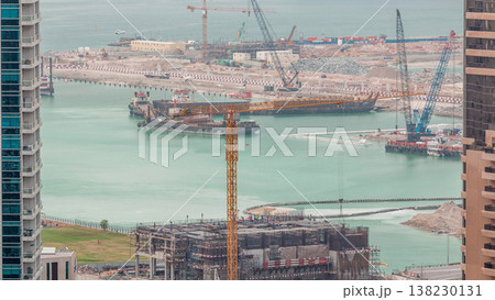 Aerial view of a skyscraper under construction with huge cranes timelapse in Dubai marina. 138230131