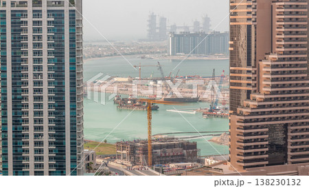 Aerial view to Dubai marina skyscrapers with construction site and Palm Jumeirah Island on background timelapse. Aerial view to Dubai marina skyscrapers with construction site and Palm Jumeirah Island on background timelapse. 138230132