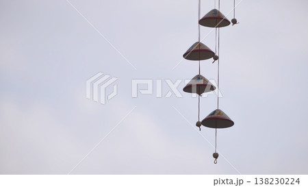 Handmade ceramic wind chime hanging against a soft, overcast sky. Handmade ceramic wind chime hanging against a soft, overcast sky. 138230224