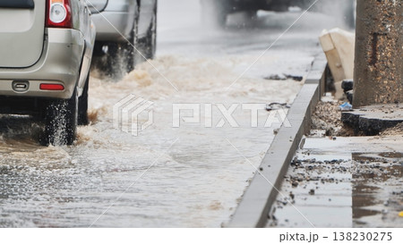 Cars driving through flooded city street, splashing water on a rainy day Cars driving through flooded city street, splashing water on a rainy day 138230275