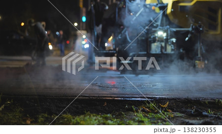 Road paving at night, construction workers laying fresh asphalt with heavy machinery 138230355