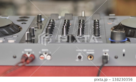 DJ controller with connected cables and knobs for mixing music at an event DJ controller with connected cables and knobs for mixing music at an event 138230356
