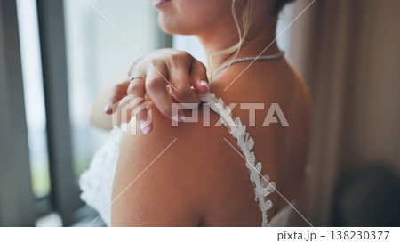 Elegant bride in profile adjusting the delicate lace strap of her wedding gown. Elegant bride in profile adjusting the delicate lace strap of her wedding gown. 138230377