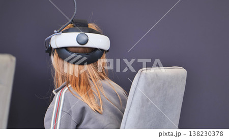 Girl experiencing virtual reality, using modern VR headset for immersive entertainment Girl experiencing virtual reality, using modern VR headset for immersive entertainment 138230378