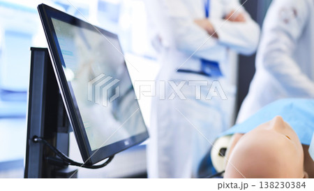 Medical students learning practicing surgery on a manikin using a simulation monitor 138230384