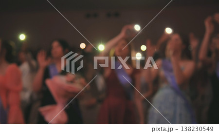 Graduates waving flashlights during commencement ceremony, celebrating their academic achievement with flowers and sashes Graduates waving flashlights during commencement ceremony, celebrating their academic achievement with flowers and sashes 138230549