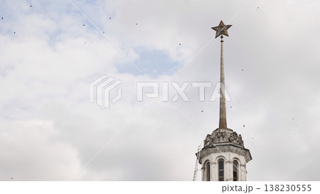 Soviet star and hammer and sickle atop a historical building spire against cloudy sky in Moscow. Soviet star and hammer and sickle atop a historical building spire against cloudy sky in Moscow. 138230555