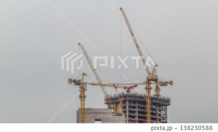 Aerial view of a skyscraper under construction with huge cranes timelapse in Dubai marina. 138230588