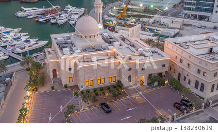 Yachts in Dubai Marina flanked by the Al Rahim Mosque and residential towers and skyscrapers aerial night to day timelapse. Yachts in Dubai Marina flanked by the Al Rahim Mosque and residential towers and skyscrapers aerial night to day timelapse. 138230619
