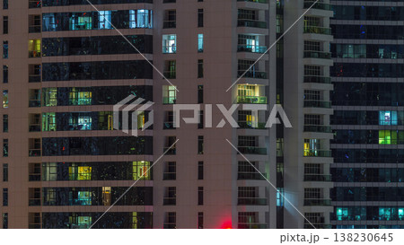 Rows of glowing windows with people in apartment building at night. Rows of glowing windows with people in apartment building at night. 138230645