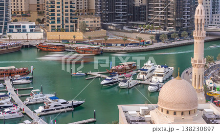 Yachts in Dubai Marina flanked by the Al Rahim Mosque and residential towers and skyscrapers aerial timelapse. 138230897