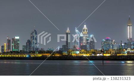 Modern Dubai city skyline timelapse at night with illuminated skyscrapers over water surface Modern Dubai city skyline timelapse at night with illuminated skyscrapers over water surface 138231323
