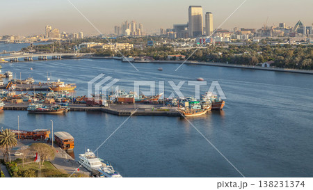 Dubai creek landscape timelapse with boats and ship in port and modern buildings in the background during sunset Dubai creek landscape timelapse with boats and ship in port and modern buildings in the background during sunset 138231374