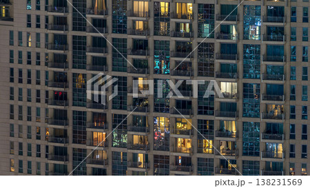 Windows of the multi-storey building of glass and steel lighting inside and moving people within timelapse 138231569