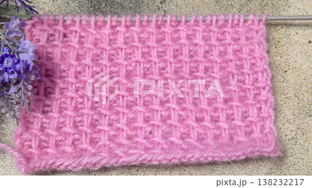 A relief openwork pattern knitted with colored yarn on a wooden background A relief openwork pattern knitted with colored yarn on a wooden background 138232217