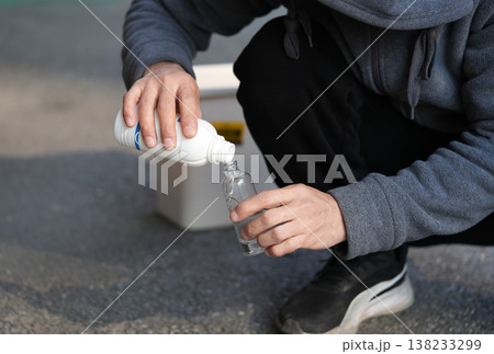 Man pouring disinfectant alcohol into a spray bottle Man pouring disinfectant alcohol into a spray bottle 138233299