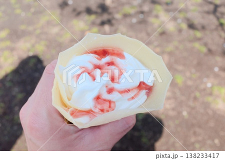 手持ちのいちごホイップクレープ、食べ歩き向け屋外スイーツ素材 138233417