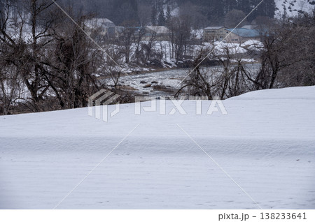 雪降る南会津の冬景色、一面の雪原と雪化粧した山並みが広がる里山の風景 雪降る南会津の冬景色、一面の雪原と雪化粧した山並みが広がる里山の風景 138233641